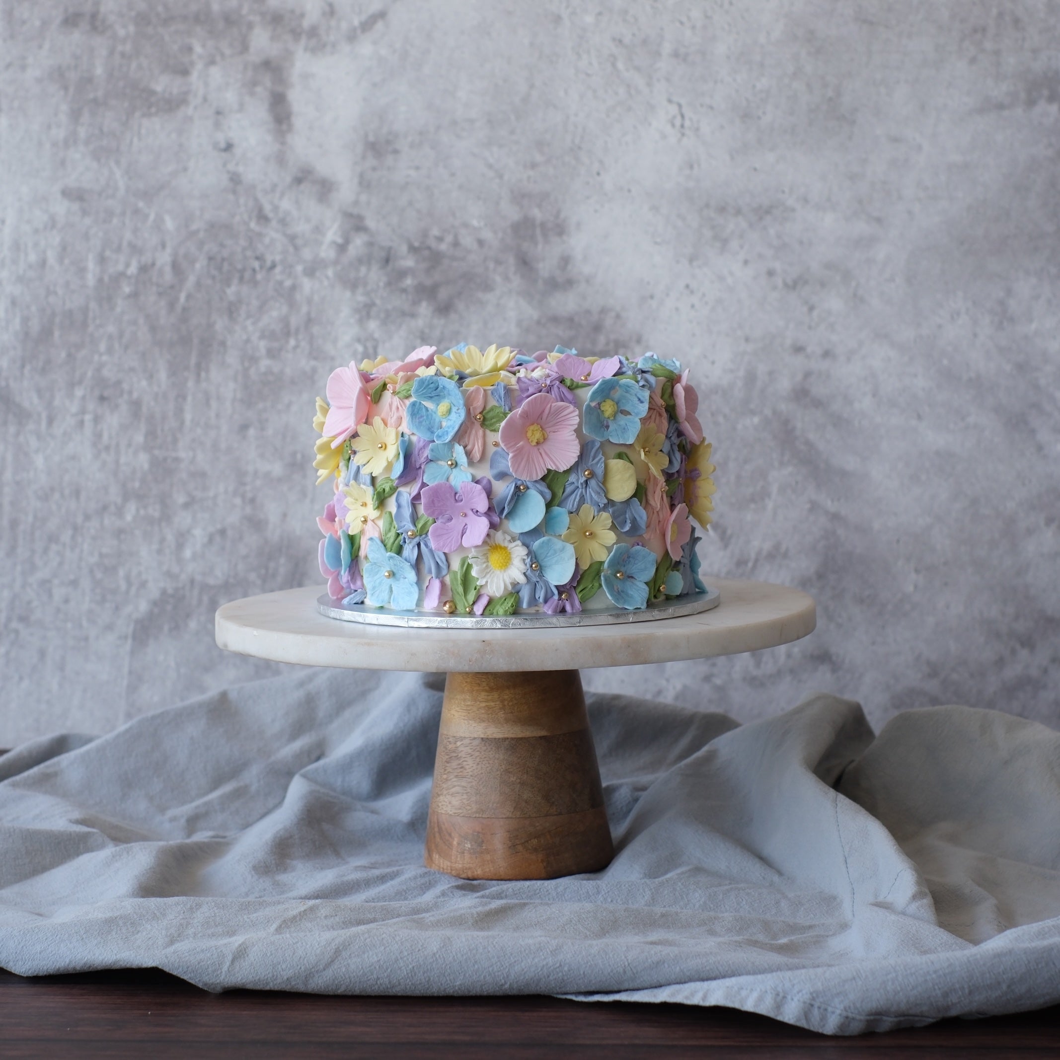 Baby in Bloom baby shower cake with pastel edible flowers in soft pink, blue and yellow pastel colours.