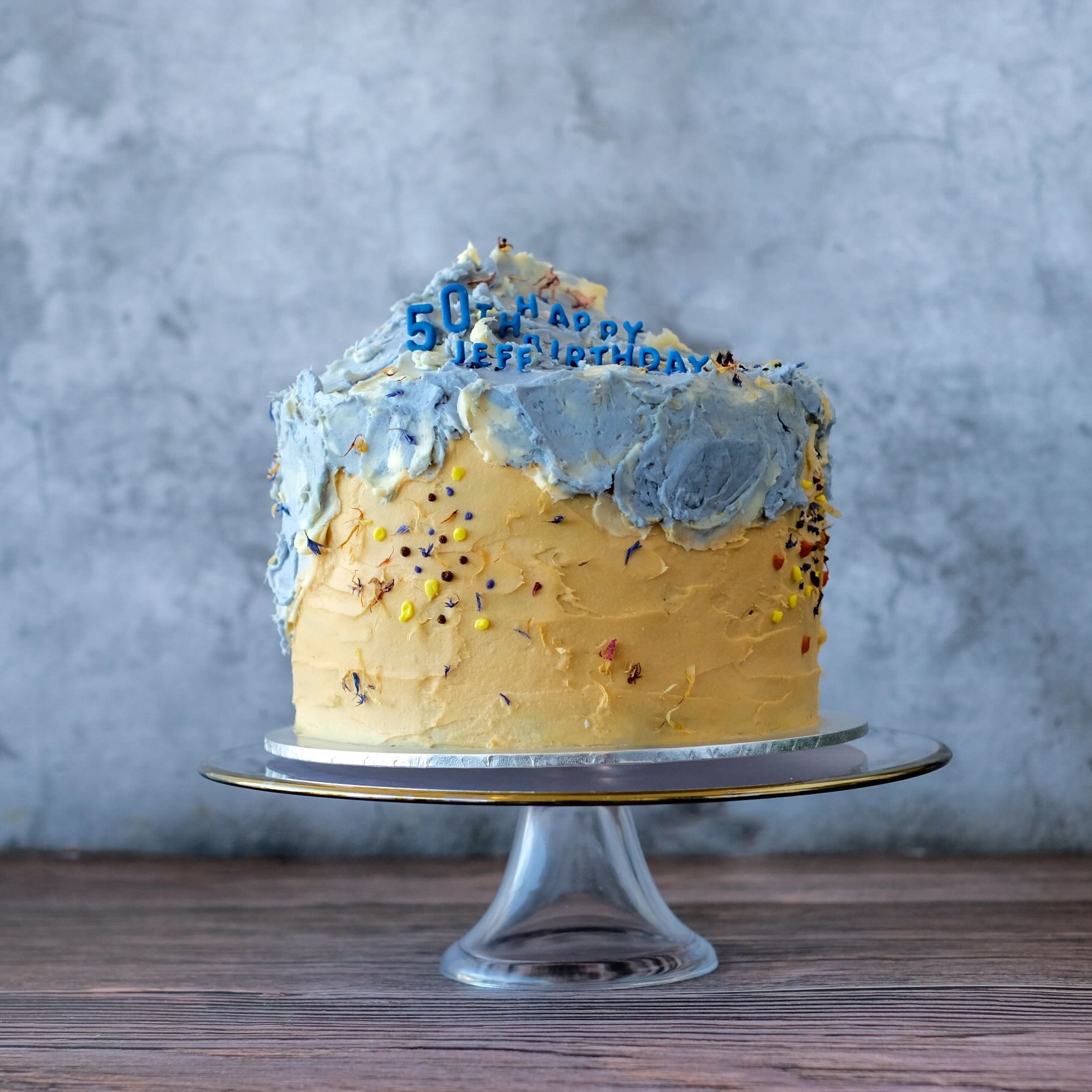 Artistic beach cake with textured buttercream layers in sand and sea colours, featuring organic strokes that mimic shoreline waves.