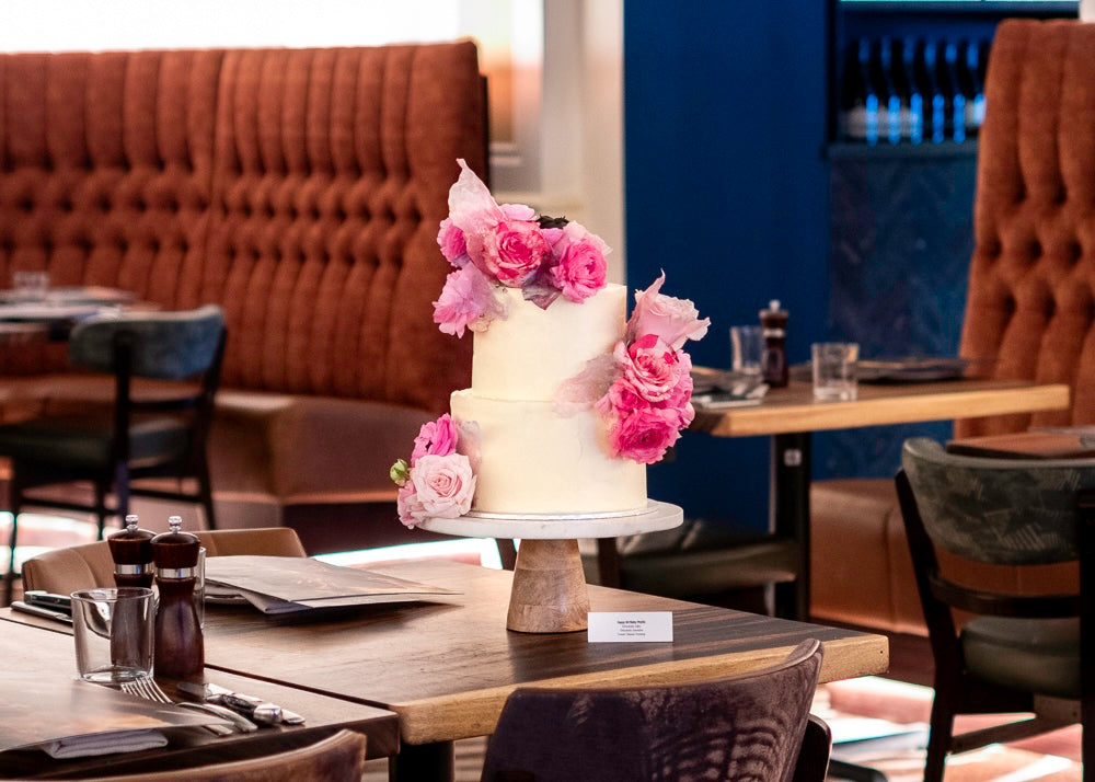 Two-tiered cake with pink flowers on display at the restaurant.