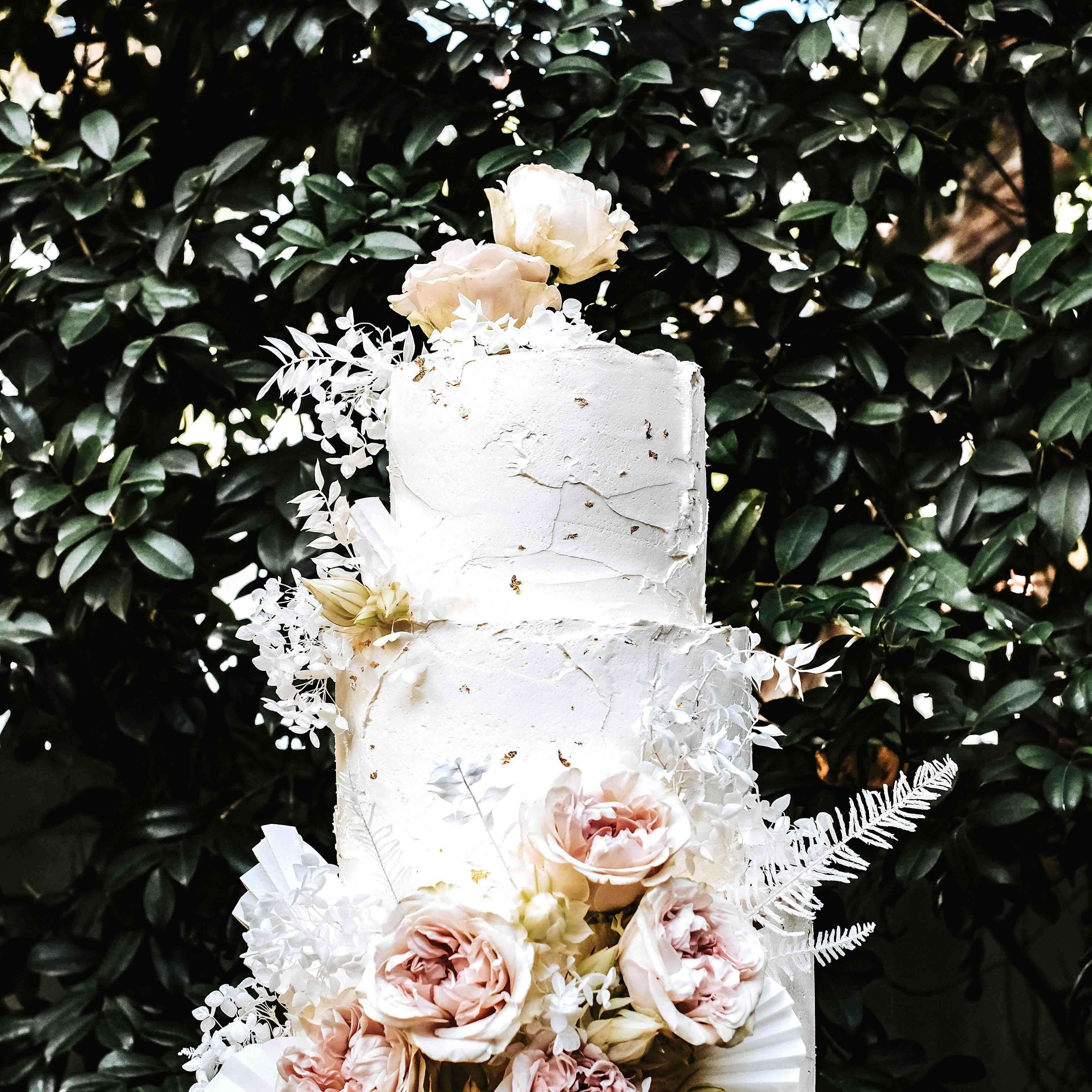 a close up of a four tier cake with boho rustic flower and white buttercream