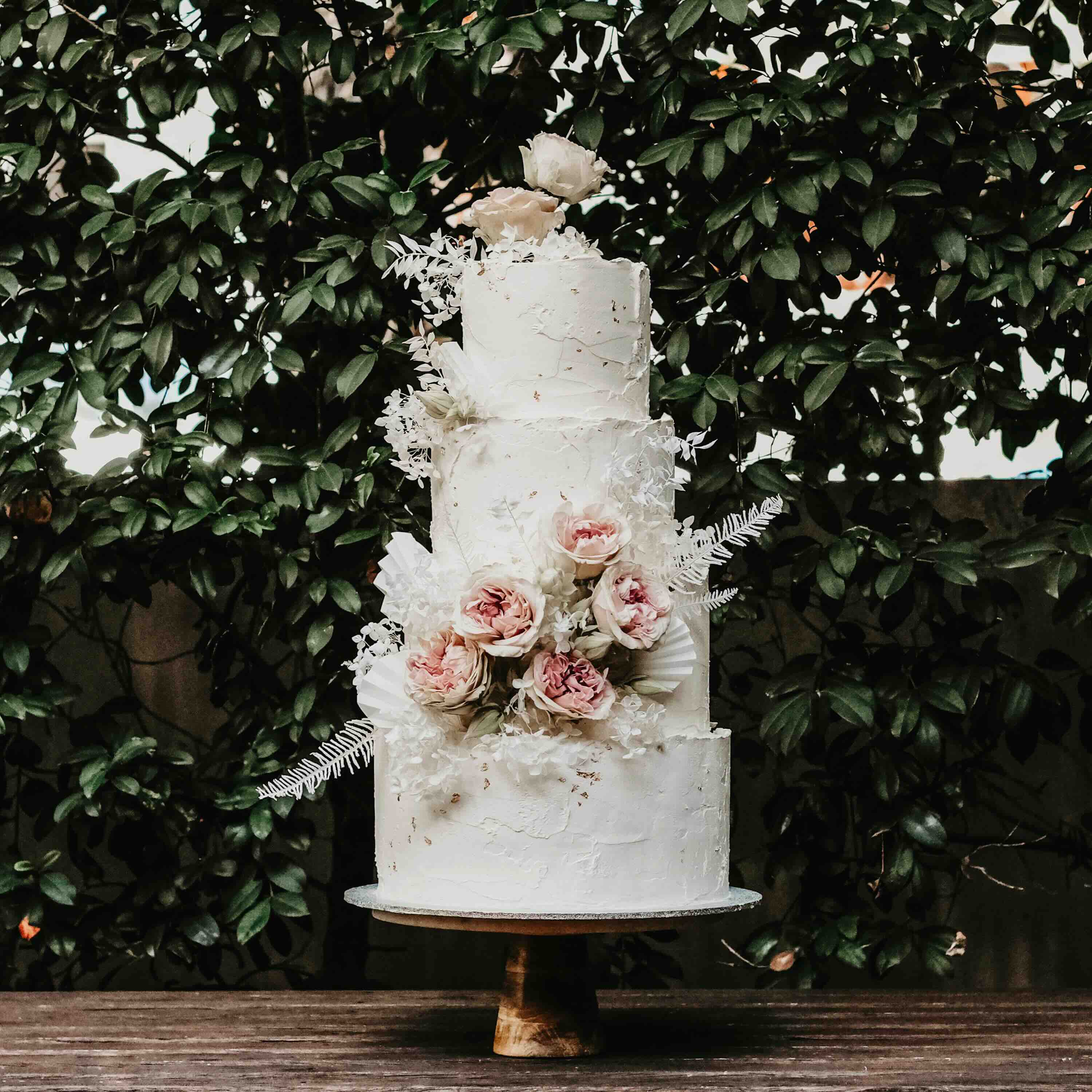 four-tiered white wedding cake with romantic rustic flowers.