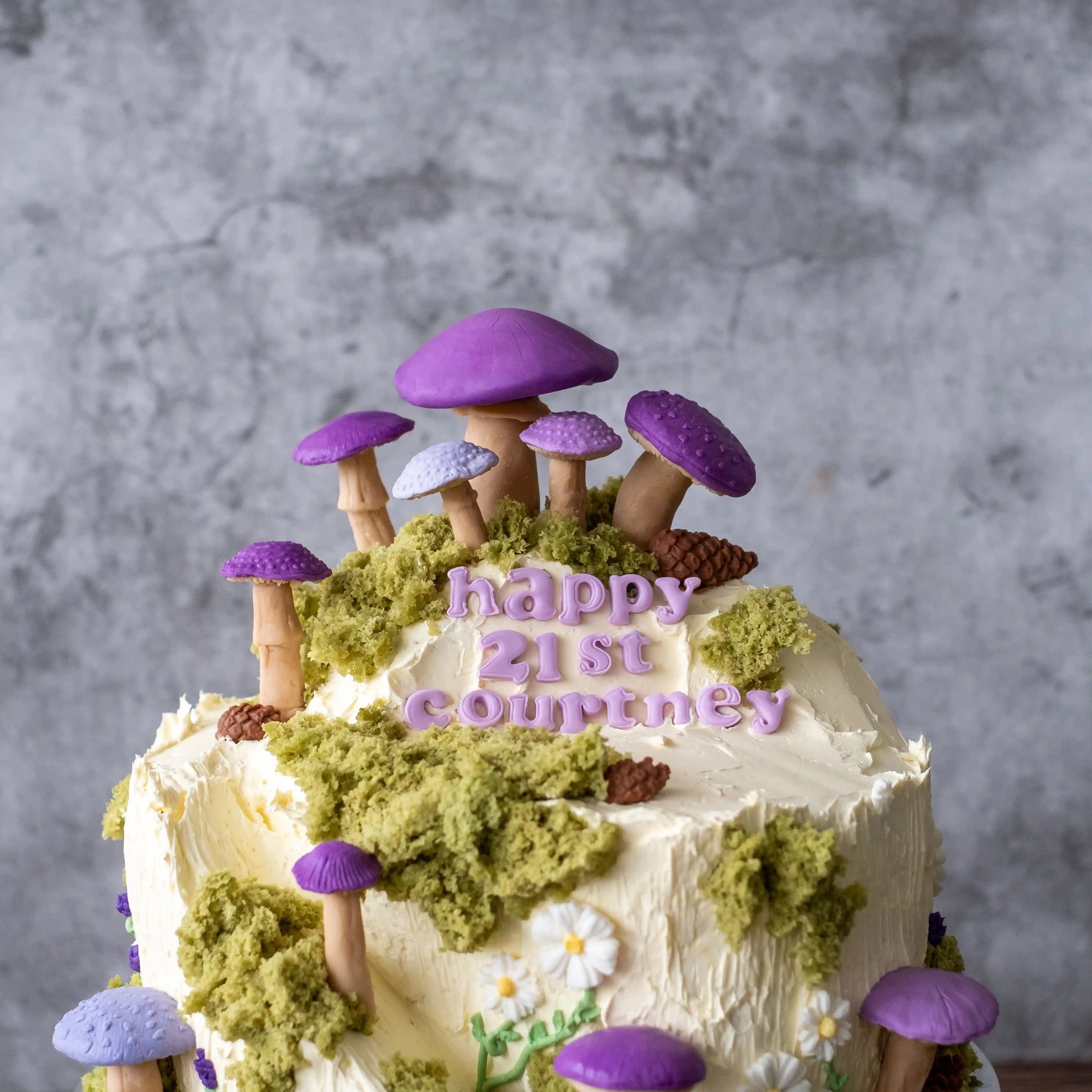 Close-up of a woodland-themed cake with purple fondant mushrooms, matcha