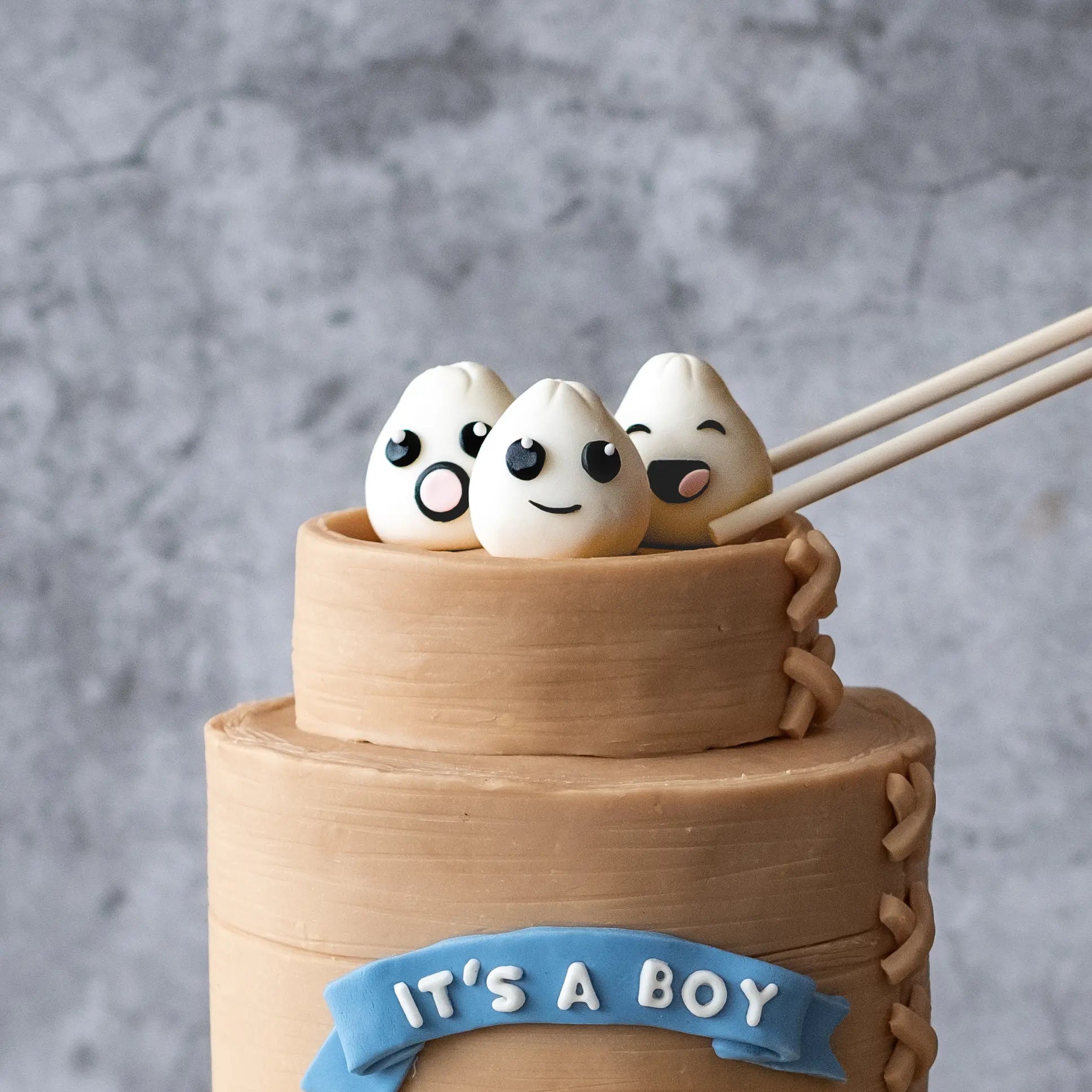 A baby shower cake topped with edible baby dumplings, designed as a custom celebration cake in Perth.