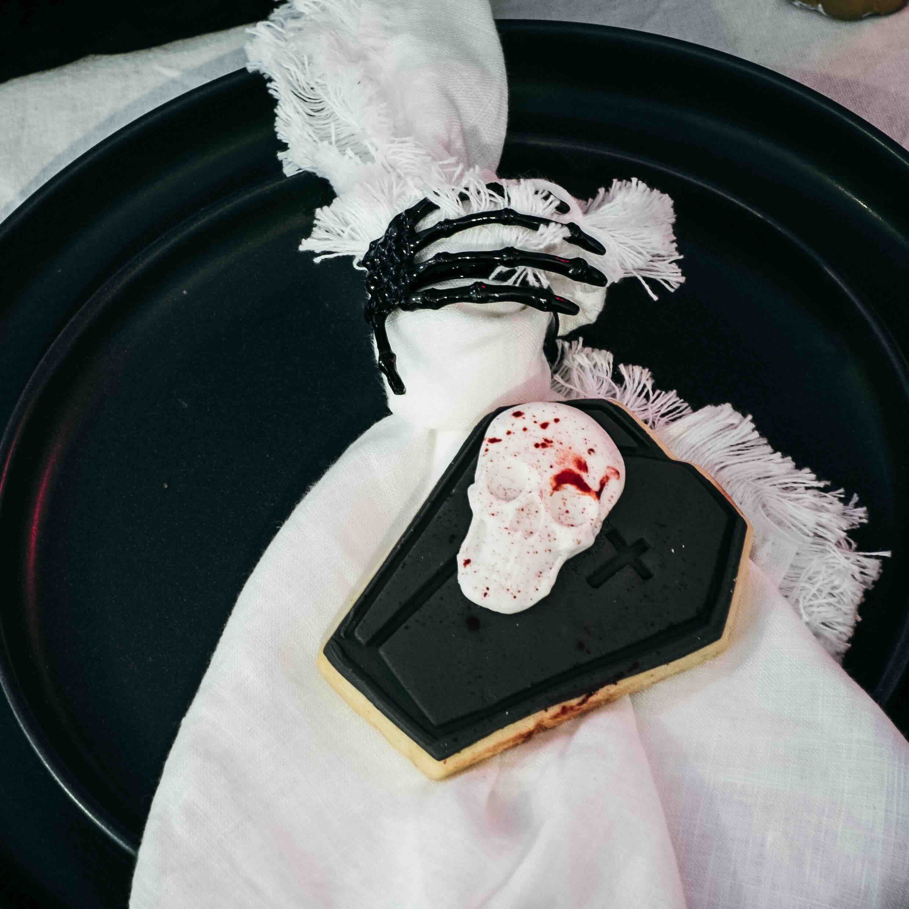 coffin shaped decorated cookies on a dark gothic styled tablescape.